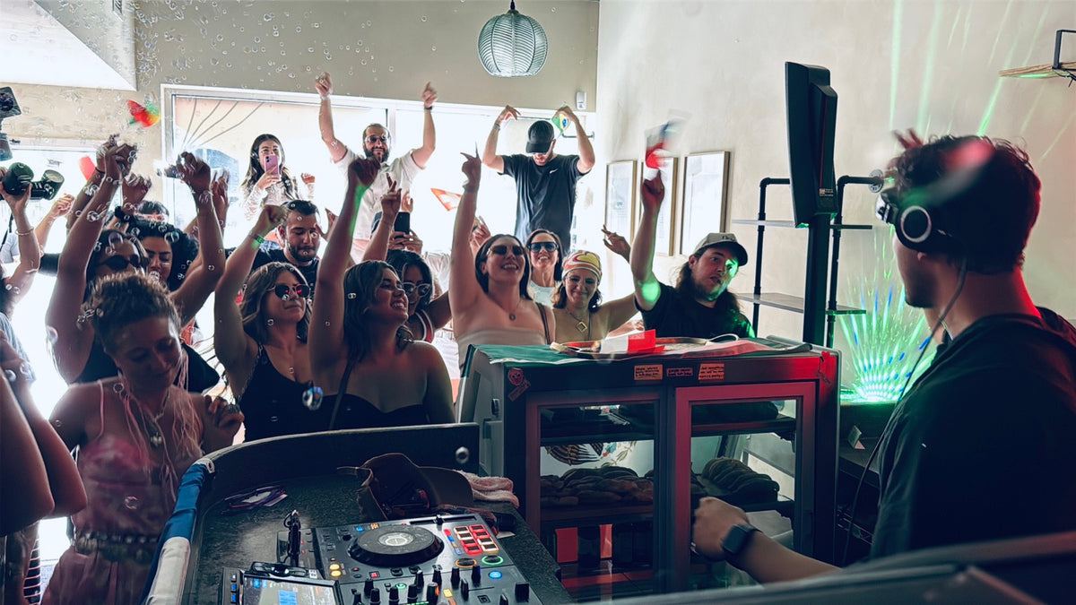 Guests dancing around the DJ booth inside Hola café